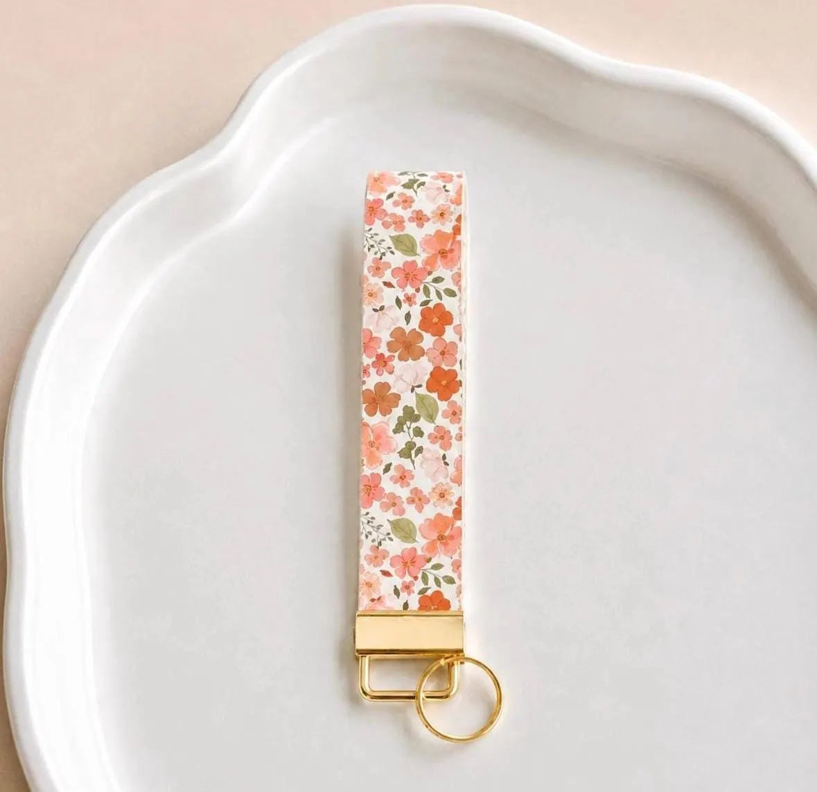 Full Bloom Wristlet keychain featuring a vibrant floral print, gold-tone hardware, and a comfortable wrist strap.