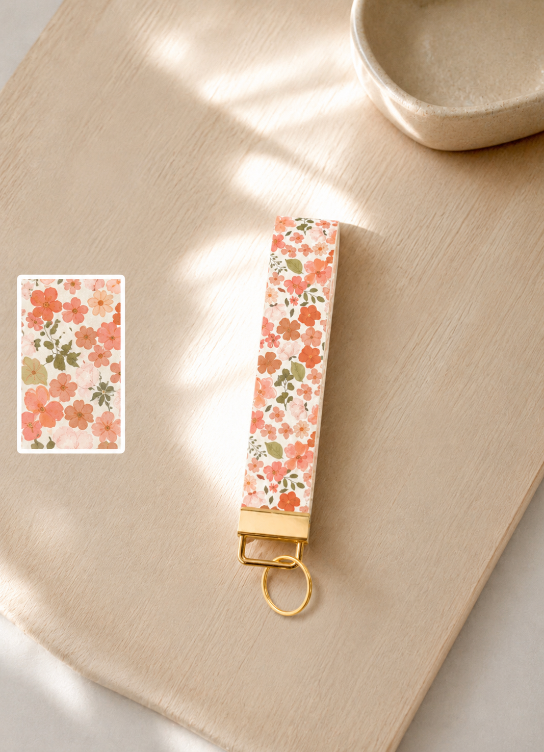 Floral patterned keychain on a beige wooden surface with a close-up inset of floral design.