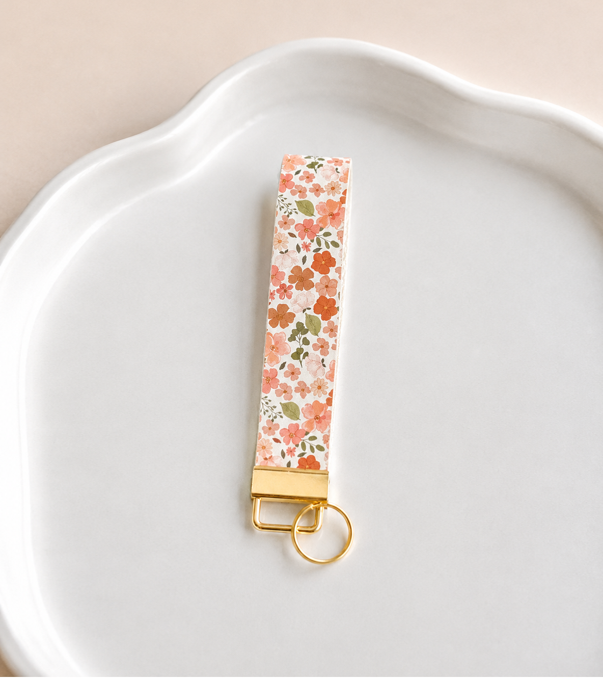 Full Bloom Wristlet keychain featuring a vibrant floral print, gold-tone hardware, and a comfortable wrist strap