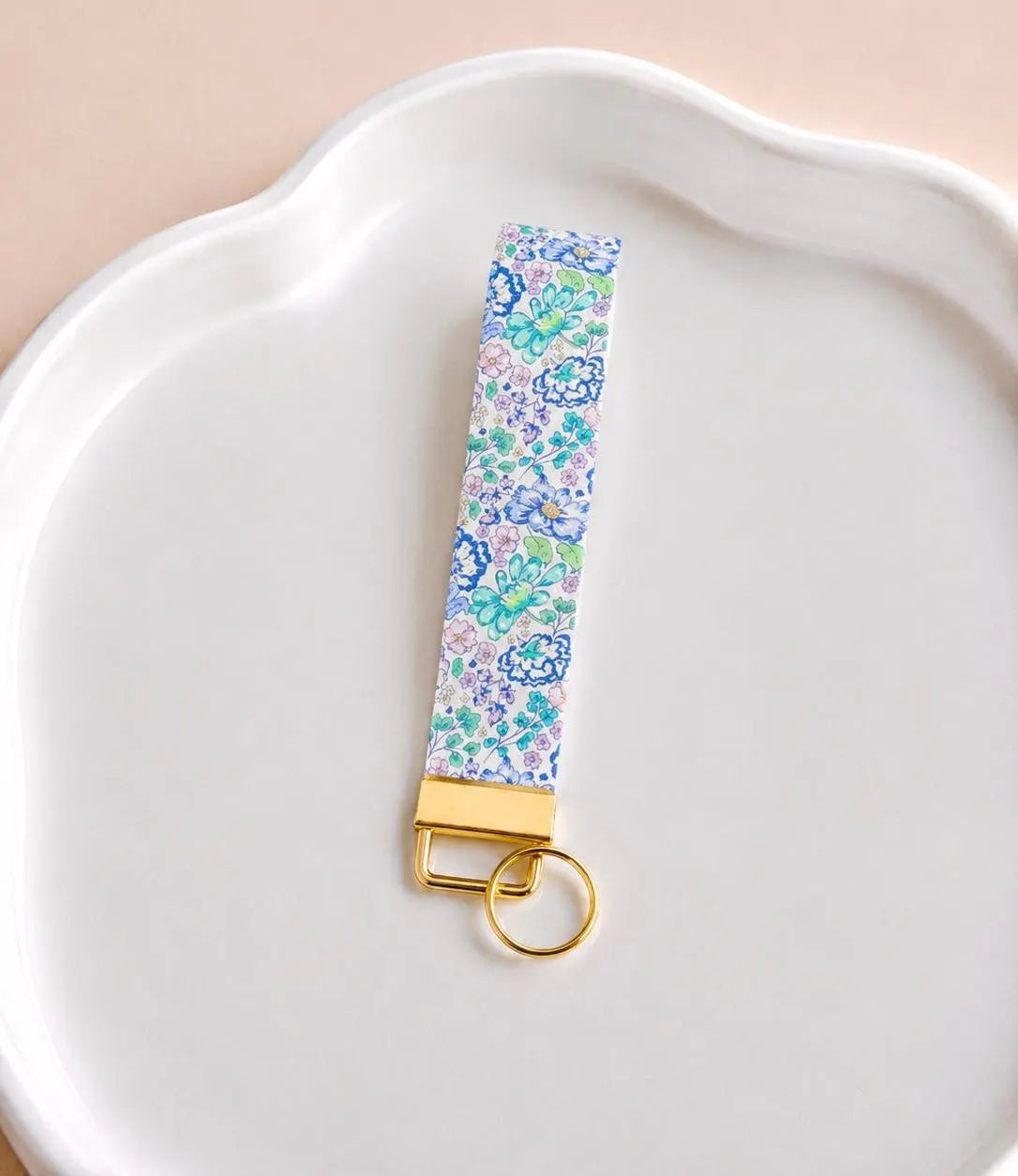 Lavender Haze wristlet keychain with blue, lavender, and mint green floral print on white scalloped tray with gold hardware