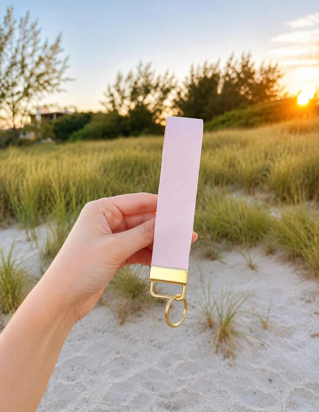 Baby pink faux leather wristlet keychain held at golden hour on the beach — Petal Pink Wristlet by Sundazed