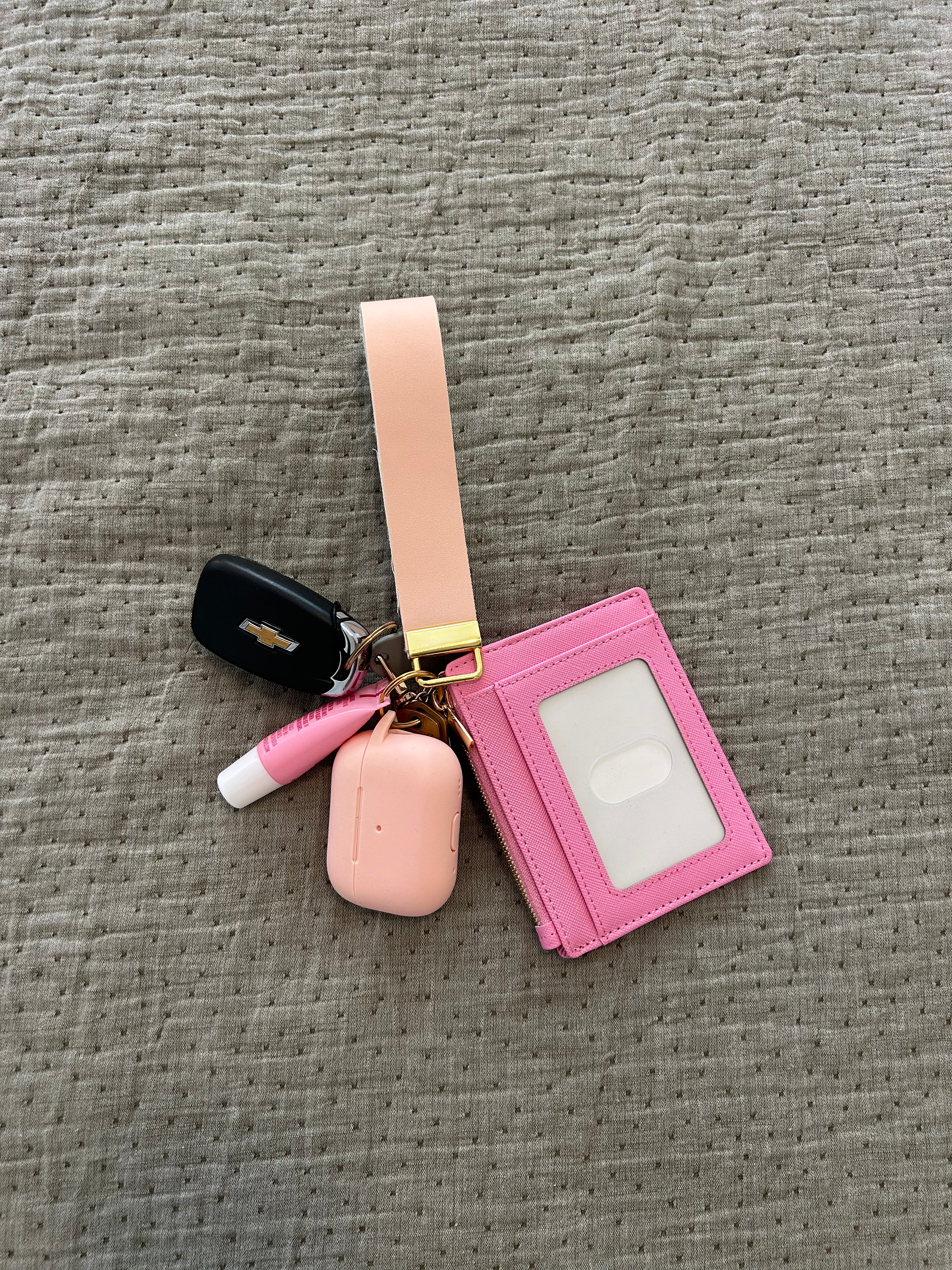 Pink keychain with card holder and key fob on a gray textured surface